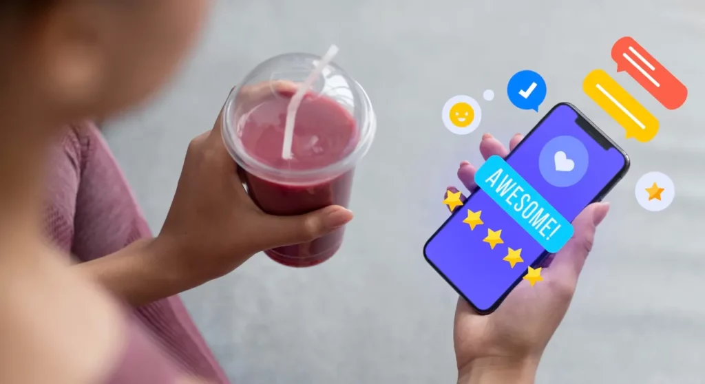 Woman holding an smoothy and smartphone showing awesome smiley check and five stars good service