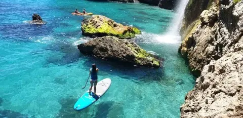 Woman riding a Stand Up Paddle boar on a route in Maro waterfall and cliff in Nerja Malaga Spain