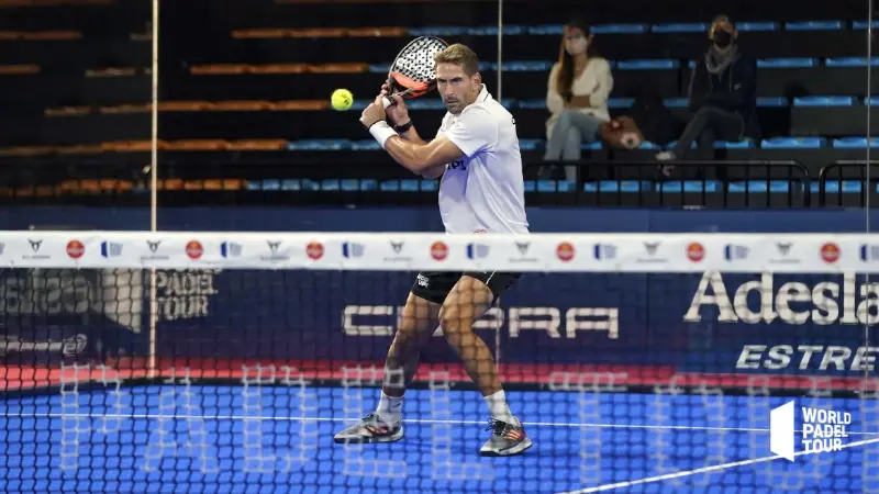 Male padel tennis player making a backhand on blue court