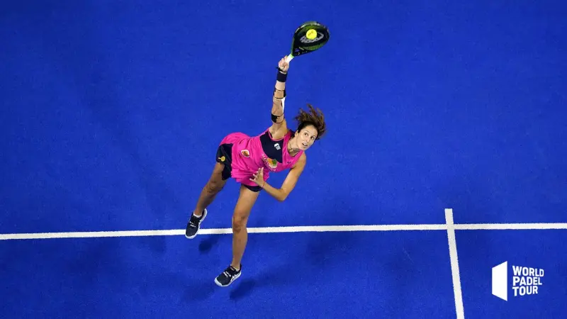 Drove view woman padel tennis player making aerial shot on blue court