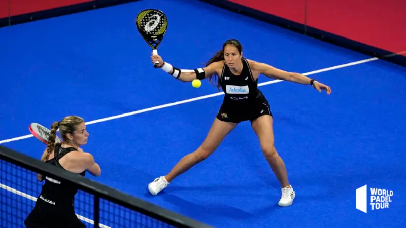side view of woman padel tennis player making a forehand stroke on blue court